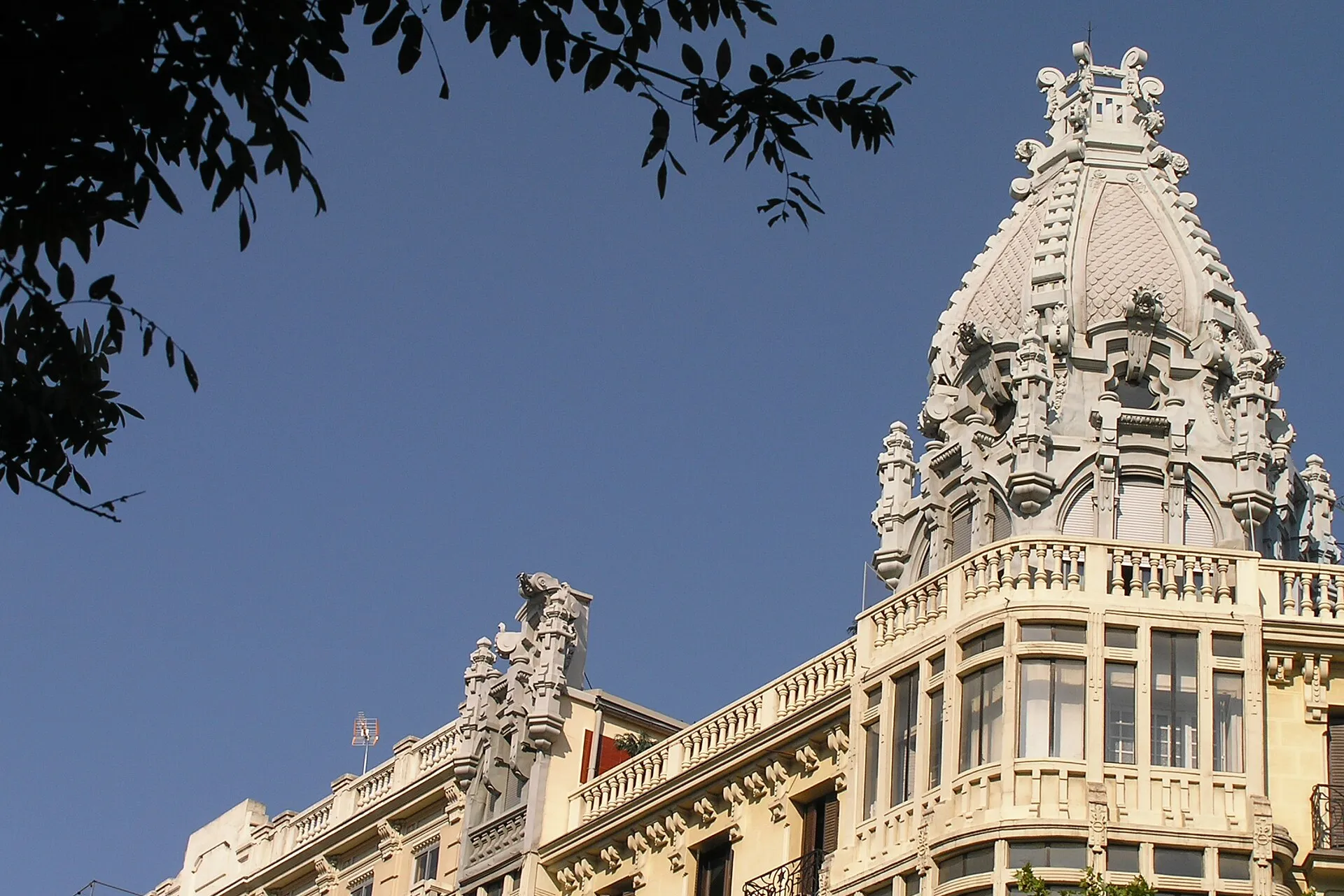 El remate blanco de un edificio del centro de Madrid contra el cielo azul.